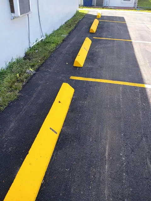 Parking Lot Repaving, Miami Beach: Painted, numbered wheel stops along the building