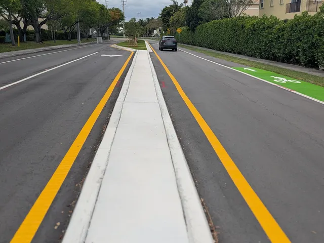 Palmetto Bay Median, Bike Lane & Striping Improvements: New raised concrete median separator between yellow edge lines, with a green bike lane on the right