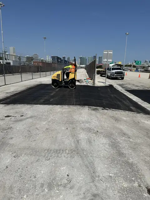Asphalt Patching, PortMiami: Compacting the patch with the port skyline behind